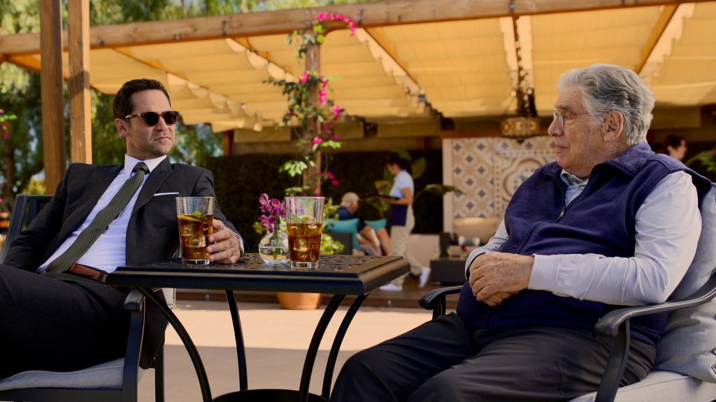 The Lincoln Lawyer characters Mickey Haller and Legal Siegel sitting and drinking iced tea at a racquet club Cr. Courtesy of Netflix © 2023