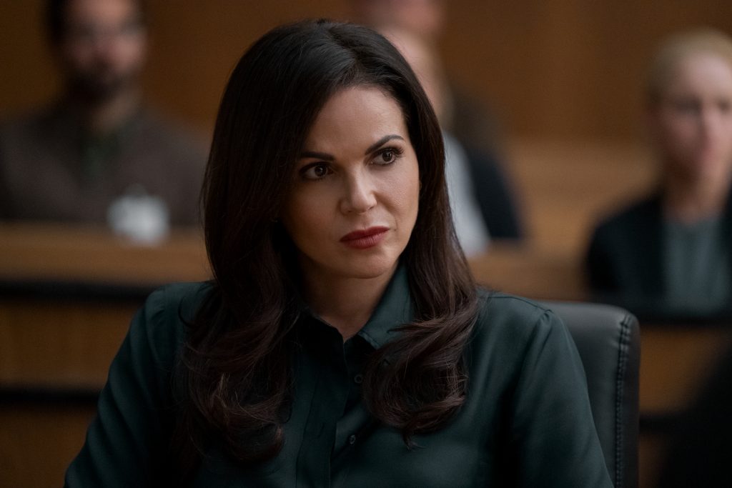 The Lincoln Lawyer character Lisa Trammell with long dark hair seated wearing a dark green blouse.