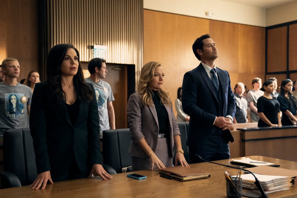 The Lincoln Lawyer characters Lisa, Lorna and Mickey stand behind the defense table in courtroom.