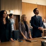 The Lincoln Lawyer characters Lisa, Lorna and Mickey stand behind the defense table in courtroom.