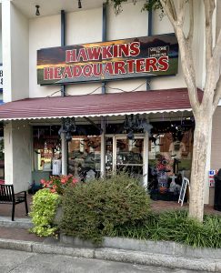 Storefront with a sign that reads Hawkins Headquarters. Stranger Things memorabilia visible.